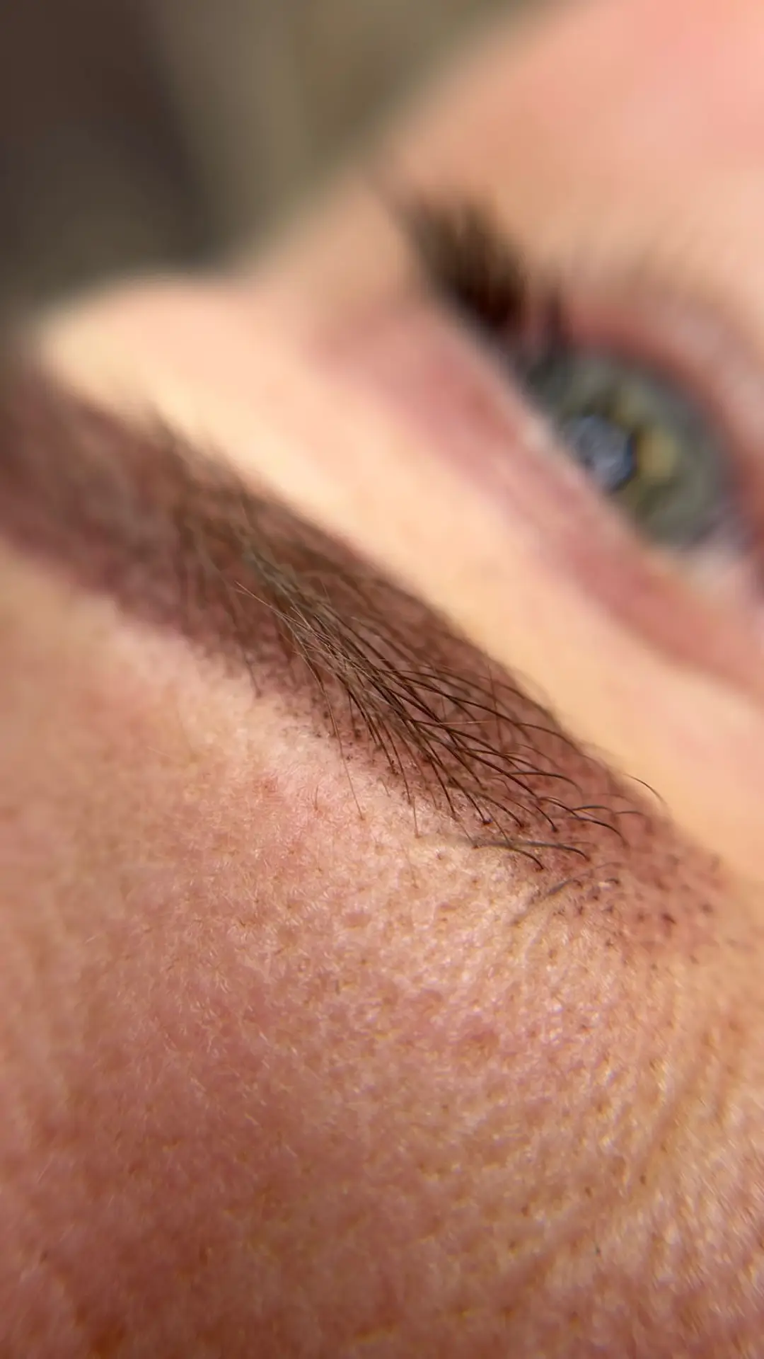 Close-up van een genezen wenkbrauw met fijne haartjes na permanente make-up